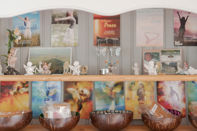 shelves and ornaments inside Relaxtherapy garden studio with peace signs and coconut bowls