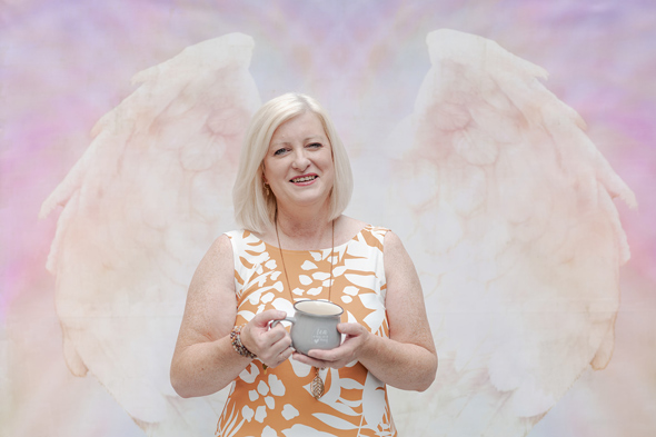 Caroline Evans, owner of Relaxtherapy, against angel wings on wall